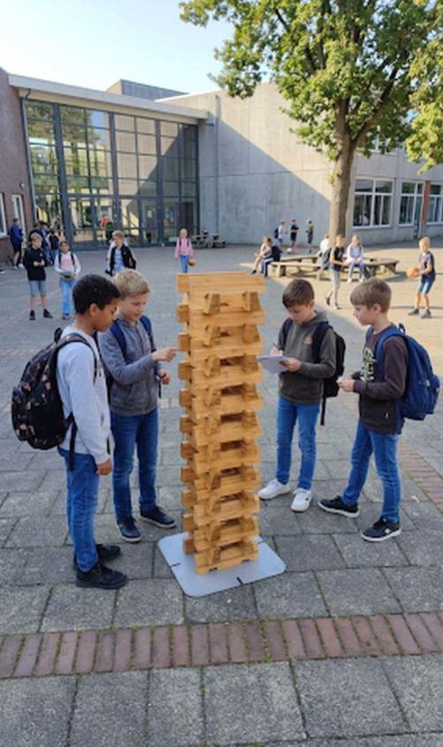4 Jungen stehen um Outdoor Lernsäule auf Schulhof, ohne Tabletts, 3.3.2026